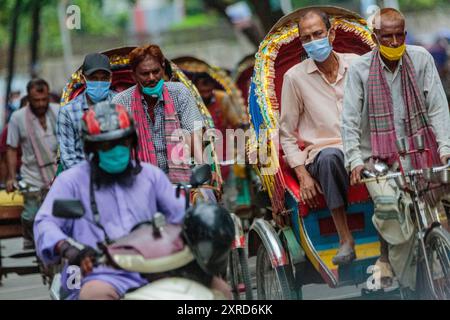 Ricksha-Walas, o risciò i conducenti con i loro passeggeri per le strade di Dacca. I residenti nella Dhaka, capitale del Bangladesh, si stanno adattando alla minaccia del virus della corona COVID 19. Foto Stock