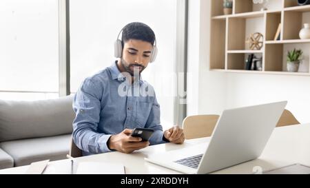 Giovane studente arabo con le cuffie che usa lo smartphone Foto Stock