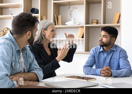 Team aziendale eterogeneo composto da colleghi seri che discutono del progetto Foto Stock
