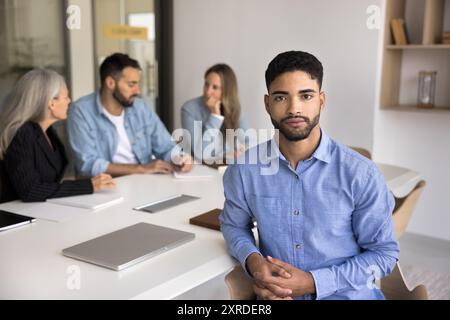 Serio e affascinante, giovane CEO arabo seduto al tavolo di riunione Foto Stock