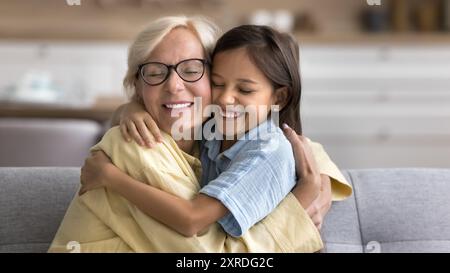 Allegra e carina nipote e felice nonna che abbraccia con amore Foto Stock