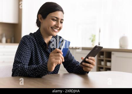 Happy Woman effettua pagamenti senza contanti utilizzando carta e smartphone Foto Stock