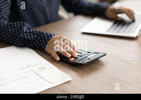 Donna che gestisce le finanze personali utilizzando laptop e calcolatrice, primo piano Foto Stock