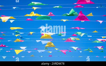 File di bandiere colorate su sfondo blu. Bunting è un decor tradizionale, di solito multicolore, decorato in occasione di eventi speciali. Foto Stock