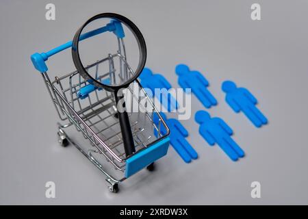 Carrello della spesa in miniatura, statuette e lente di ingrandimento. Segmentazione del mercato e concetto di analisi dei clienti. Foto Stock