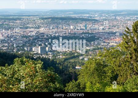 Panoramablick vom Uetliberg auf Zürichs Westen Das Bild zeigt einen weiten Panoramablick vom Uetliberg auf den westlichen Teil von Zürich und das Limmattal. Im Vordergrund ragen dichte Wälder hervor, die den unteren Teil des Uetlibergs bedecken, während sich dahinter die Stadt ausbreitet. Zu erkennen sind die markanten Hochhäuser der Hardau-Hochhäuser, der prime Tower und weitere moderne Gebäude, die sich zwischen den älteren Wohngebieten und Industrieanlagen erheben. Zürich Zürich Schweiz *** Vista panoramica di Zurichs a ovest dall'Uetliberg l'immagine mostra un'ampia vista panoramica dell'ovest Foto Stock