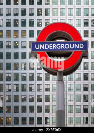 Trasporto per l'iconico logo della metropolitana di Londra per la rete metropolitana della capitale. Un'icona culturale, la rotonda si trova di fronte a uno dei grattacieli. Foto Stock