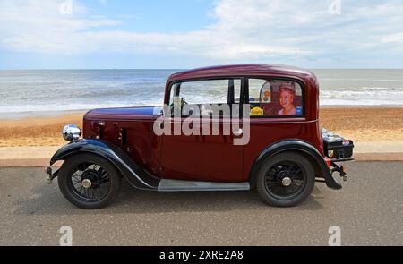 Austin Seven vintage parcheggiata sulla spiaggia lungomare e sul mare sullo sfondo. Foto Stock