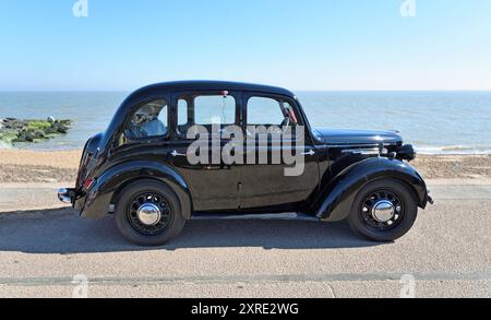 Classic Black Austin 8 Saloon parcheggiato sulla spiaggia lungomare e sul mare sullo sfondo. Foto Stock