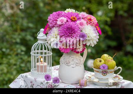 disposizione dei tavoli con bouquet di dahlias bianche e rosa, zinnie e garofani, mele e lanterne da tavolo Foto Stock