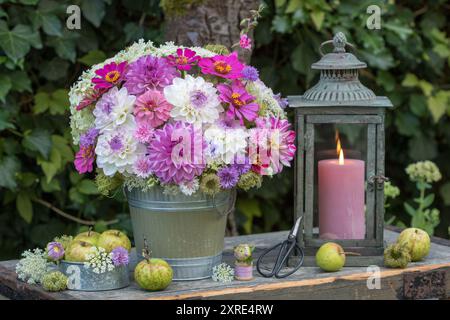 accordo con bouquet di dahlias, zinnie, garofani e carote selvatiche, mele e lanterne d'annata Foto Stock