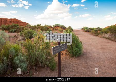 Un cartello con la scritta "Arches National Park" guida gli escursionisti verso Landscape Arch, Tunnel Arch e Pine Tree Arch. La testata e la roccia rossa circostante Foto Stock