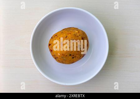 Delizioso bharta kathaler bichi in una ciotola bianca su sfondo di legno. Il bhorta di semi di jackfruit è un piatto bengalese molto gustoso e nutriente. Vista dall'alto. Foto Stock