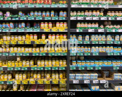 Uno scaffale con molti vasetti di pappe per bambini. Gli scaffali dei supermercati sono rivestiti con diversi tipi di alimenti per bambini. Foto Stock