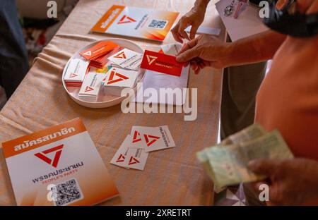 Un sostenitore del Partito Popolare sceglie gli adesivi con il logo del partito durante l'evento di registrazione all'adesione al punto di registrazione, dove il Partito Popolare ha ufficialmente aperto la registrazione all'adesione. Il Partito Popolare è un nuovo partito politico in Thailandia fondato dopo lo scioglimento del Partito Move Forward. È stato lanciato nell'agosto 2024. A partire dalle 17:30 del 10 agosto 2024, il partito ha 35.890 membri registrati e ha ricevuto 18.878.074 THB in donazioni. Il partito mira a raggiungere 100.000 membri entro il primo mese. (Foto di Pongmanat Tasiri/SOPA Images/Sipa USA) Foto Stock