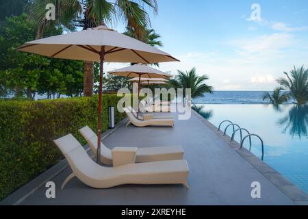 Giardino con sedie a sdraio e area salotto vicino alla piscina Foto Stock