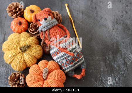 Decorazione di Halloween con zucche, giocattolo Fox all'uncinetto e filato di lana arancione su sfondo grigio con spazio per il testo. Regalo autunnale fatto a mano. Foto Stock