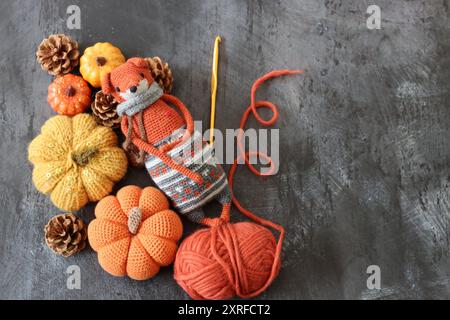 Decorazione di Halloween con zucche, giocattolo Fox all'uncinetto e filato di lana arancione su sfondo grigio con spazio per il testo. Regalo autunnale fatto a mano. Foto Stock