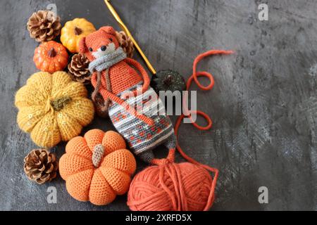 Decorazione di Halloween con zucche, giocattolo Fox all'uncinetto e filato di lana arancione su sfondo grigio con spazio per il testo. Regalo autunnale fatto a mano. Foto Stock