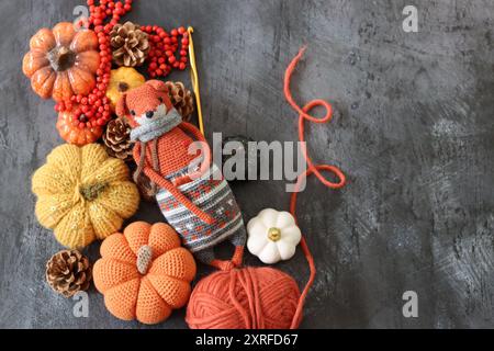 Decorazione di Halloween con zucche, giocattolo Fox all'uncinetto e filato di lana arancione su sfondo grigio con spazio per il testo. Regalo autunnale fatto a mano. Foto Stock