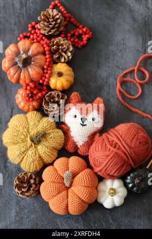 Decorazione di Halloween con zucche, giocattolo Fox all'uncinetto e filato di lana arancione su sfondo grigio con spazio per il testo. Regalo autunnale fatto a mano. Foto Stock