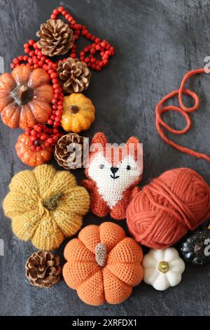 Decorazione di Halloween con zucche, giocattolo Fox all'uncinetto e filato di lana arancione su sfondo grigio con spazio per il testo. Regalo autunnale fatto a mano. Foto Stock