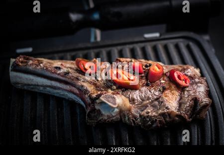 Bistecca di manzo ribeye grigliata con peperoncino sul grill, vista dall'alto. Carne alla griglia fatta in casa Foto Stock