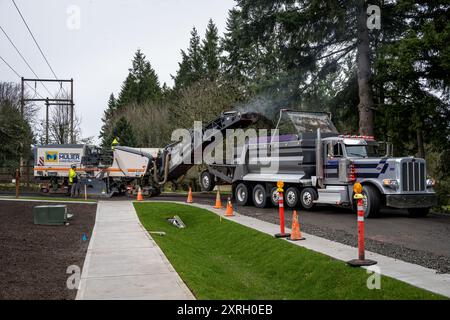 KIRKLAND, WA – 31 GENNAIO 2024: Il personale addetto alla costruzione di strade lavora in una strada residenziale, fresatrice rottamazione e rimozione del vecchio asfalto e alimentazione Foto Stock