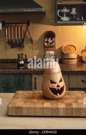 Zucca scolpita in cima a un asse di legno, sullo sfondo la cucina. Preparare Halloween, festa e tradizione Foto Stock