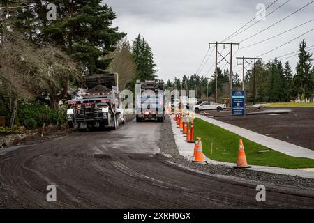 KIRKLAND, WA – 31 GENNAIO 2024: Il personale addetto alla costruzione di strade lavora in una strada residenziale rimuovendo il vecchio asfalto e il dumper pieno di detriti da trasportare Foto Stock