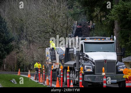 KIRKLAND, WA – 31 GENNAIO 2024: Il personale addetto alla costruzione di strade lavora in una strada residenziale, fresatrice rottamazione e rimozione del vecchio asfalto e alimentazione Foto Stock