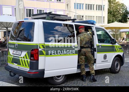 Augusta, Baviera, Germania - 10 agosto 2024: Un ufficiale di polizia militare delle forze armate tedesche in uniforme mimetica si trova di fronte a un veicolo di polizia militare. Immagine simbolica dell'ordine militare e della sicurezza fornita dalla polizia militare della Bundeswehr *** Ein Feldjäger der Bundeswehr a Tarnuniform steht vor einem Feldjägerfahrzeug. Symbolbild militärische Ordnung und Sicherheit, die durch die Militärpolizei der Bundeswehr gewährleistet wird Foto Stock