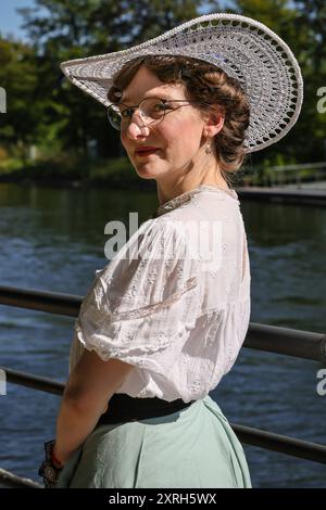 Henrichenburg, Waltrop, Germania. 10 agosto 2024. Una giovane signora in abito vittoriano vicino al canale. I fan dello steampunk, i gruppi e i visitatori, molti in costumi d'epoca retrò-futuristica o vittoriana, si divertiranno il primo giorno dell'annuale festival e mercato del Giubileo di Steampunk. Quest'anno, il festival coincide con il 125° anniversario dello storico impianto di risalita di Henrichenburg Boat Lift, sito patrimonio industriale lungo il canale Dortmund-EMS. Crediti: Imageplotter/Alamy Live News Foto Stock