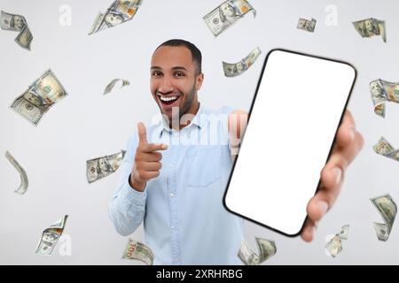 Uomo felice che punta al telefono cellulare con schermo vuoto sotto la pioggia di denaro su sfondo bianco Foto Stock