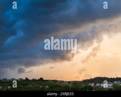 Le nuvole di tempesta si insinuano su un tranquillo quartiere degli Stati Uniti, con una brillante pausa nel cielo che offre uno scorcio di speranza in una serata estiva. Foto Stock