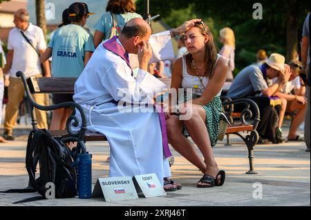 Un sacerdote cattolico che benedice e dà assoluzione a un penitente dopo la confessione a Medjugorje durante Mladifest 2024, la festa giovanile. Foto Stock