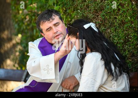 Un sacerdote cattolico che benedice e dà assoluzione a un penitente dopo la confessione a Medjugorje durante Mladifest 2024, la festa giovanile. Foto Stock