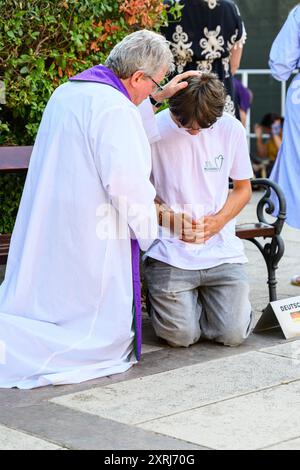 Un sacerdote cattolico che benedice e dà assoluzione a un penitente dopo la confessione a Medjugorje durante Mladifest 2024, la festa giovanile. Foto Stock