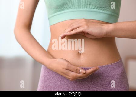 Digestione sana. Donna che tiene qualcosa vicino alla pancia dentro, primo piano Foto Stock