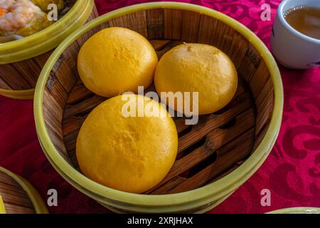 Cestino di cottura a vapore contenente panini di crema pasticcera, servito come parte di dim sum, popolare nel sud-est asiatico, in un ristorante a George Town, Penang, Malesia. Foto Stock