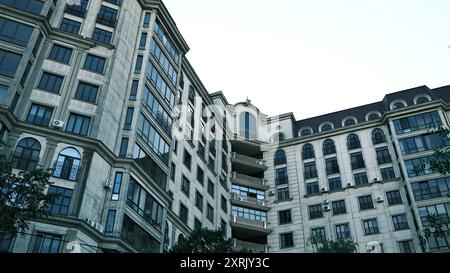 Maestoso edificio a più piani con elementi neoclassici e moderni, caratterizzato da finestre ad arco, balconi e facciate decorate Dettagli in un ambiente cittadino Foto Stock