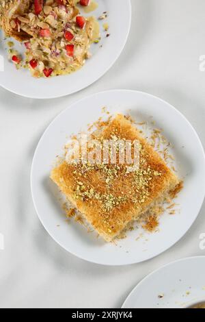 Kunefe arabo da dessert, kunafa, kadayif con pistacchio in polvere e formaggio, servito caldo, molto dolce. Dolce tradizionale turco. Dessert libanese di Kunaf Foto Stock