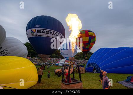 Le mongolfiere fanno esplodere i fuochi mentre si preparano a decollare alla 46a Bristol International Balloon Fiesta, un festival annuale di mongolfiera gratuito, che è il più grande evento del suo genere in Europa, che si svolge durante il fine settimana a Bristol. Data foto: Domenica 11 agosto 2024. Foto Stock