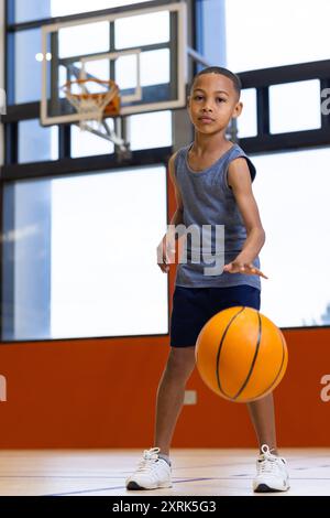 Dribbling basket, ragazzo che pratica nella palestra scolastica, concentrato sul miglioramento delle abilità Foto Stock