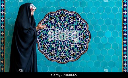 Yazd, Iran - 2 maggio 2019: Donna iraniana che prega di fronte a un'opera d'arte piastrellata nella Moschea Jameh di Yazd Foto Stock