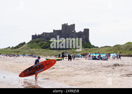 La gente ama il clima caldo sulla spiaggia di Bamburgh nel Northumberland. Data foto: Domenica 11 agosto 2024. Foto Stock