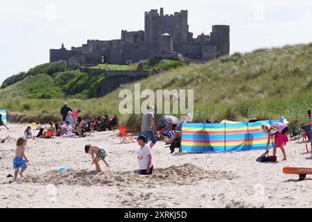 La gente ama il clima caldo sulla spiaggia di Bamburgh nel Northumberland. Data foto: Domenica 11 agosto 2024. Foto Stock