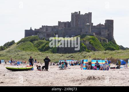 La gente ama il clima caldo sulla spiaggia di Bamburgh nel Northumberland. Data foto: Domenica 11 agosto 2024. Foto Stock