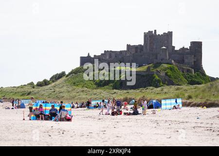La gente ama il clima caldo sulla spiaggia di Bamburgh nel Northumberland. Data foto: Domenica 11 agosto 2024. Foto Stock