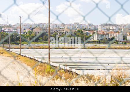 Sistema di coltivazione all'aperto per la produzione di microalghe in un parco eco-business, con edifici residenziali sullo sfondo Foto Stock